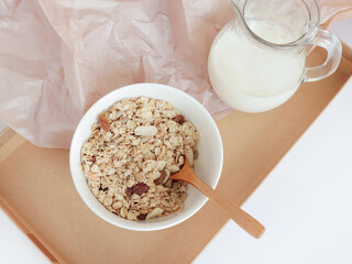 Oatmeal and milk on a tray. Muesli for breakfast. Healthy diet. White background, craft tray. The right food. Morning. Food for the student. Menu. Ingredients. Recipe.