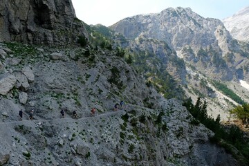 Beautiful mountain views on trail from Theth Valley to Valbona Valley in Albanian Alps. Sihouettes of tourists on path. It is one of the most beautiful high mountain trails.