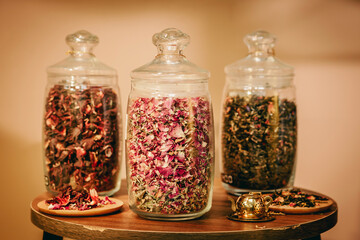 Three glass containers full of different sort of dried tea leaves with different colours