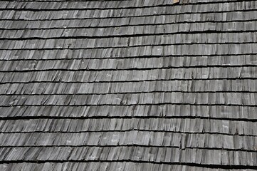 Wooden vintage shingle roof texture, sunlit by summer daylight sunshine. 