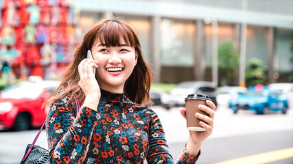 Young asian woman using mobile smart phone at Singapore city streets - Technology life style...