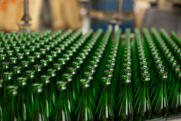 Glass factory, industrial production of glass containers. A lot of empty glass bottles as a background of green glass containers with copy space. Bottles for drinks. Technological work at the factory.