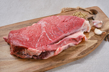 Raw steak on cutting board ready to cook. Fresh cut of beef on wooden kitchen board with spices and garlic on a granite table. Selective focus