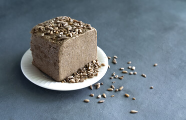 halva from sunflower seeds on a white plate with seeds, on a gray background. National traditional Turkish halva . High quality photo