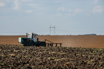 Fototapeta premium Farmer in tractor preparing land with seedbed cultivator
