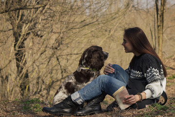 Beautiful woman and brown cocker spaniel in the forest