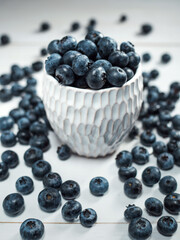 Crockery with juicy blueberries on a white table, top view