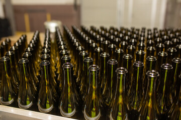 Glass factory, industrial production of glass containers. A lot of empty glass bottles as a background of green glass containers with copy space. Bottles for drinks. Technological work at the factory.