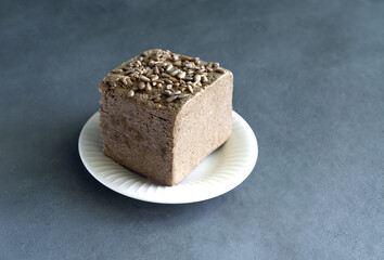 halva from sunflower seeds on a white plate with seeds, on a gray background. National traditional Turkish halva . High quality photo
