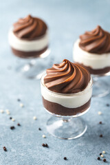 A dark chocolate mousse with white chocolate mousse dessert in a glass with milk chocolate decoration on top