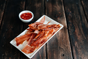 Dried chicken cut into strips on a wooden board with salt, pepper, adjiga, ketchup. High quality photo
