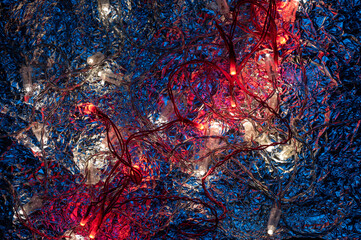 New Year's multi-colored diode garlands glow against the background of crumpled metal foil. The...