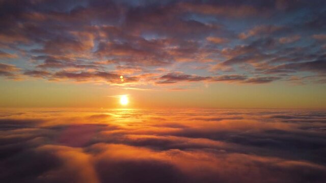Aerial footage of setting sun up in the sky. Dramatic landscape over the clouds with sun just touching the horizon