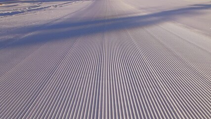 Close view of ski slope recently prepared for a sunny ski day. Manchester snow at sunrise.