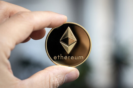 Ethereum cryptocurrency physical coin held between two fingers
