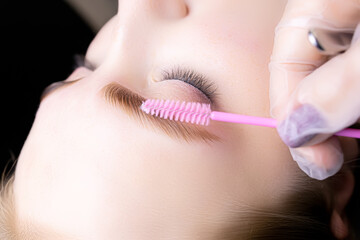 close-up of the model's dyed and laminated hairs, the master holds a brush in front of the eyebrows