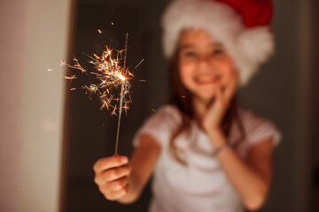 a girl holding sparklers in Santa's hat. the christmas miracle