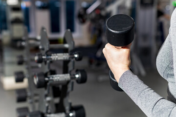 the girl is holding a dumbbell, the background is blurred