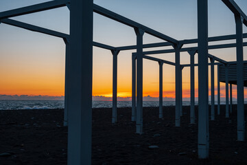 pillars on the shore during sunset, silhouettes of the pillars of the structure on the beach