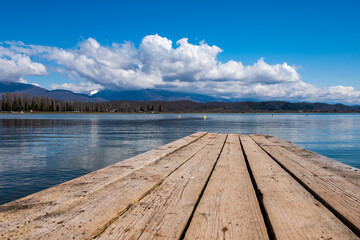wooden pier on the lake, blue cloudy sky and mountain landscape