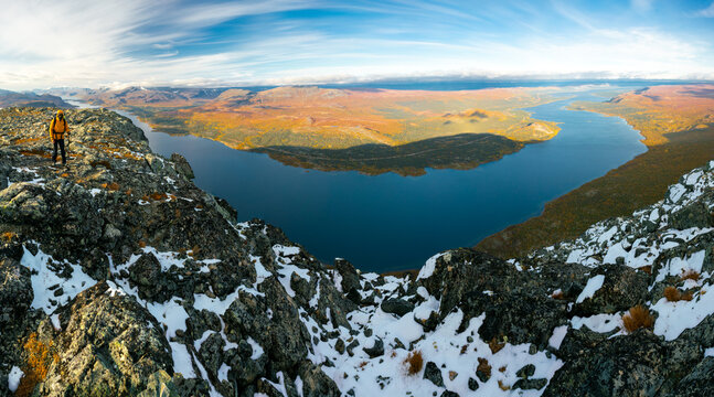 Male hiker overlooking epic view of vast arctic landscape of Stora Sjofallet National Park, Sweden, on autumn day. Mountains and valleys of Lapland. Langas lake. View from the top of Lulep Gierkav.