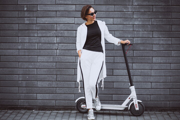 Fototapeta na wymiar Young woman dressed in white riding scooter