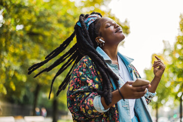 Young woman enjoying dancing and listening music outdoors
