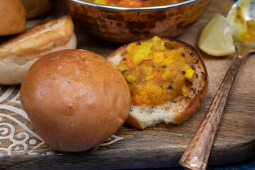 Vegetarian indian pav bhaji board: mixed potato and vegetables curry with butter toasted bund and side dishes