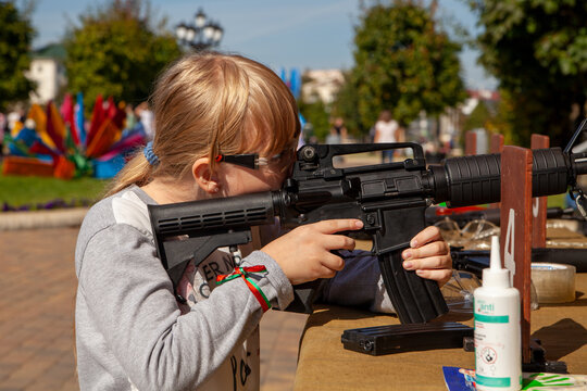 A girl in the park fires an M16A1 at a shooting range.