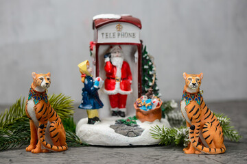 Christmas toy Santa Claus in a red telephone booth with a Christmas tree and a little girl on the side and two tigers sitting in front
