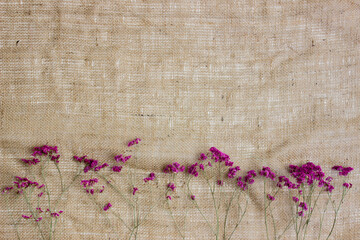 Purple flowers over the brown fabric with copy space.