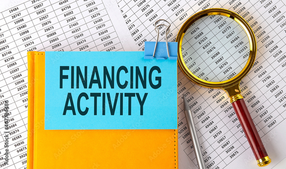 Aufkleber financing activity text on sticker on notebook with magnifier and chart. business concept