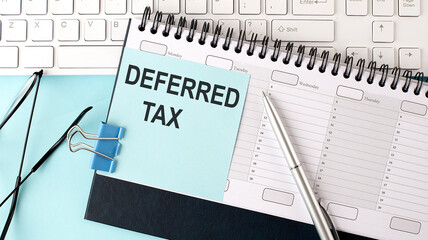 DEFERRED TAX text on blue sticker on the planning and keyboard,blue background - obrazy, fototapety, plakaty