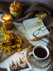 Cozy autumn background, coffee cup, notebook for notes, decorative pumpkin, seasonal flowers, candle, and autumn leaves