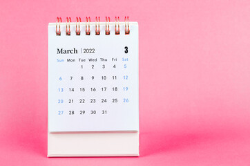 March 2022 desk calendar on pink background.