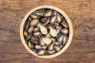 Black dry watermelon seeds in wooden bowl.