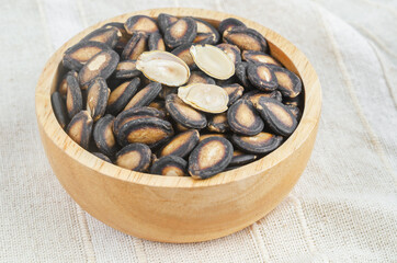 Black dry watermelon seeds in wooden bowl
