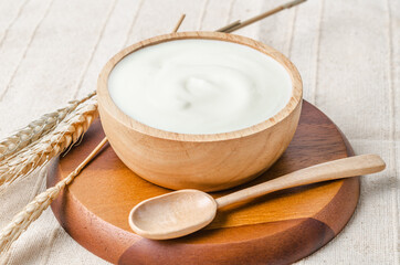 Greek yogurt in a wooden bowl and dry barley.
