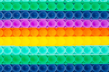 Background of rainbow colored simple dimple pop it. Fashionable and modern anti stress toy for children and adults