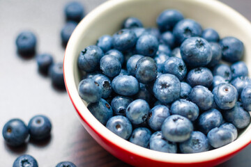 Blueberries in a red bowl on wooden table.