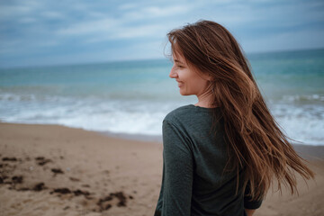 Obraz premium woman enjoying sea air on autumn beach before thunderstorm