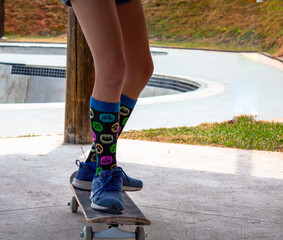 Closeup legs of a girl riding skateboard wear fun socks on the skate park