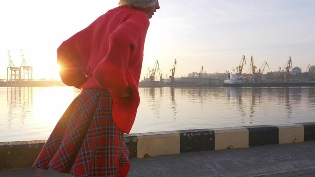 Stylish teenage girl rollerskating at sunrise, urban sports, fun leisure activity in sea port, teenage lifestyle