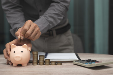 saving money and accounting concept. business man putting coin insert to piggy bank and make accounting book for finance management to investment and saving.