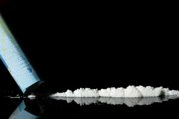 Man hands rolls banknote for using cocaine powder lines. Drug addiction concept. A line of coke on...