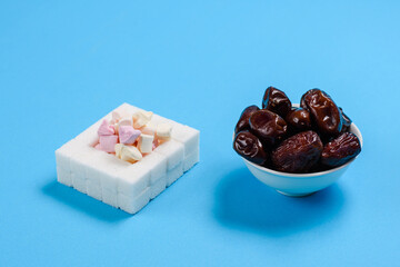 Artificial sweets and natural dried dates on a blue background. The concept of replacing sugar and sweets with natural healthy products.