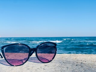 Fototapeta na wymiar sunglasses on the beach on sea background