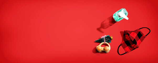 Face mask and a sanitizer bottle with a toy car carrying a Christmas tree - flat lay