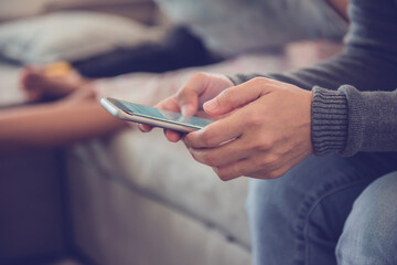 Young woman sitting using smartphone on sofa at home.