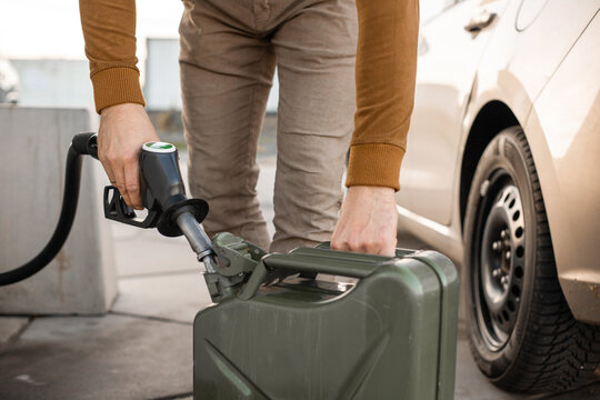 Man refilling canister with fuel on the petrol station. Close up view. Gasoline, diesel is getting more expensive.